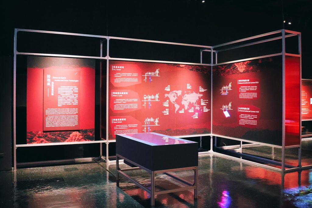 Technologies for geothermal energy development | ThinkGeoEnergy - Geothermal News & Insights Exhibit hall with red informational panels and silver metal frames on a dark background.
