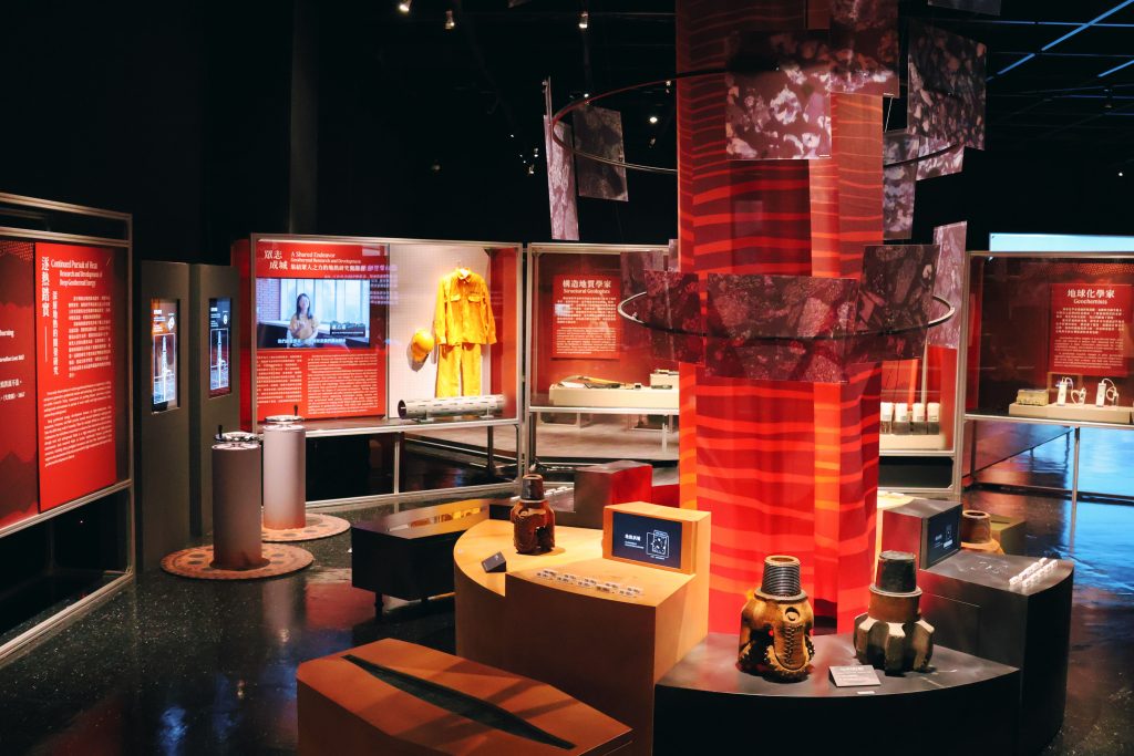 Yuanshan deep well drilling | ThinkGeoEnergy - Geothermal News & Insights Museum exhibit with red panels and large red-striped pillars displaying geological artifacts and text panels in Chinese and English.