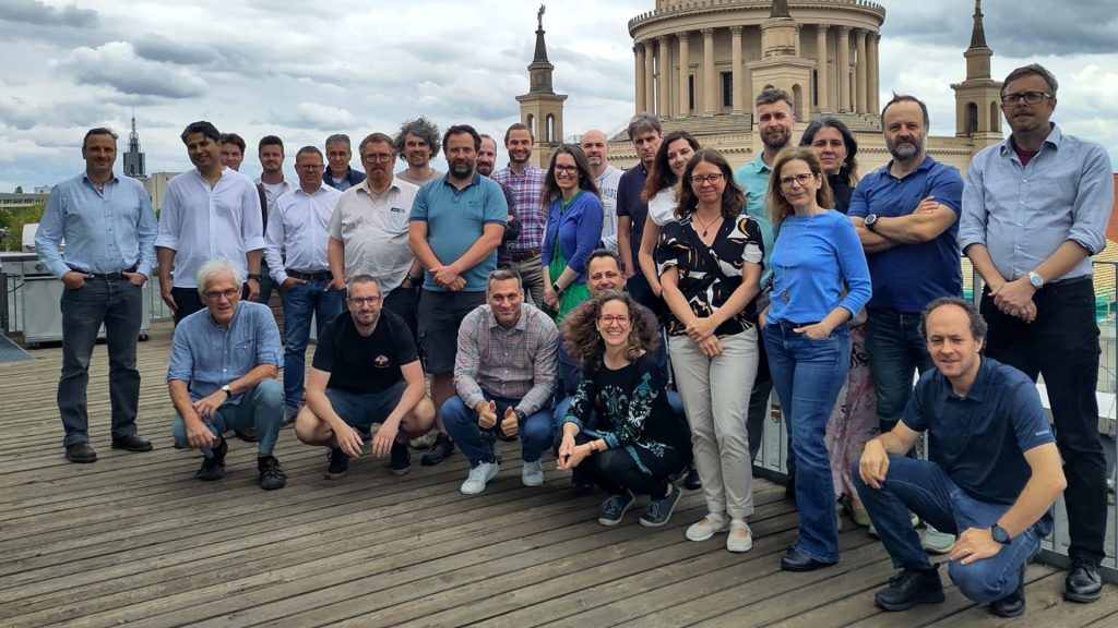 uplift kickoff | ThinkGeoEnergy - Geothermal News & Insights Group of people posing on a wooden rooftop with a classical domed building in the background, suggesting a team photo outdoors in a city setting.